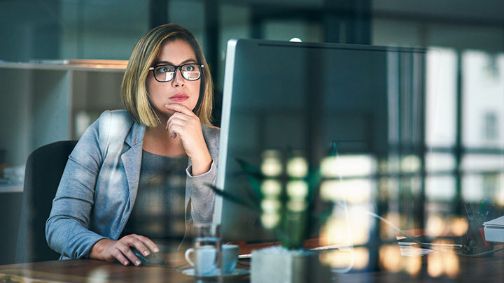 A professional woman focused on a computer screen in a modern office.