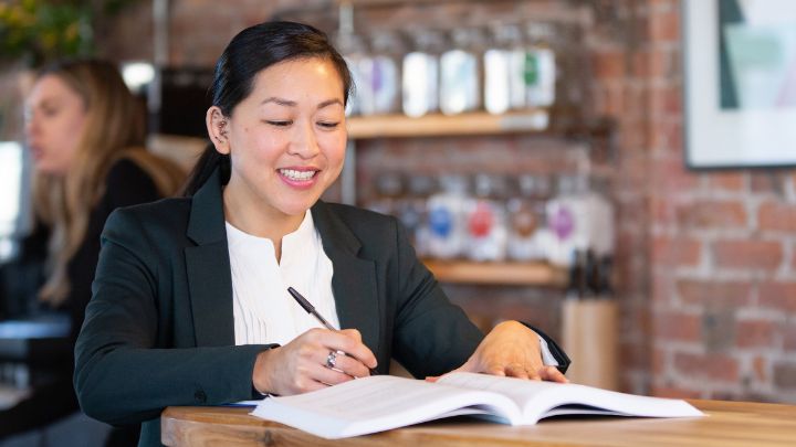 Woman in coffee shop, writing on notepad