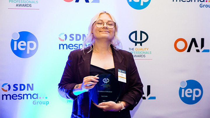 Dani Smith Dani Smith from the compliance team proudly holding her ‘Compliance Professional’ award in front of a branded event backdrop.