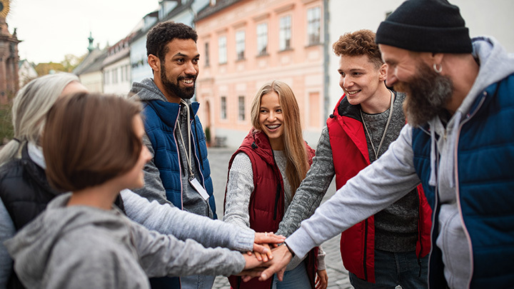 A group of people with their hands joined in the middle