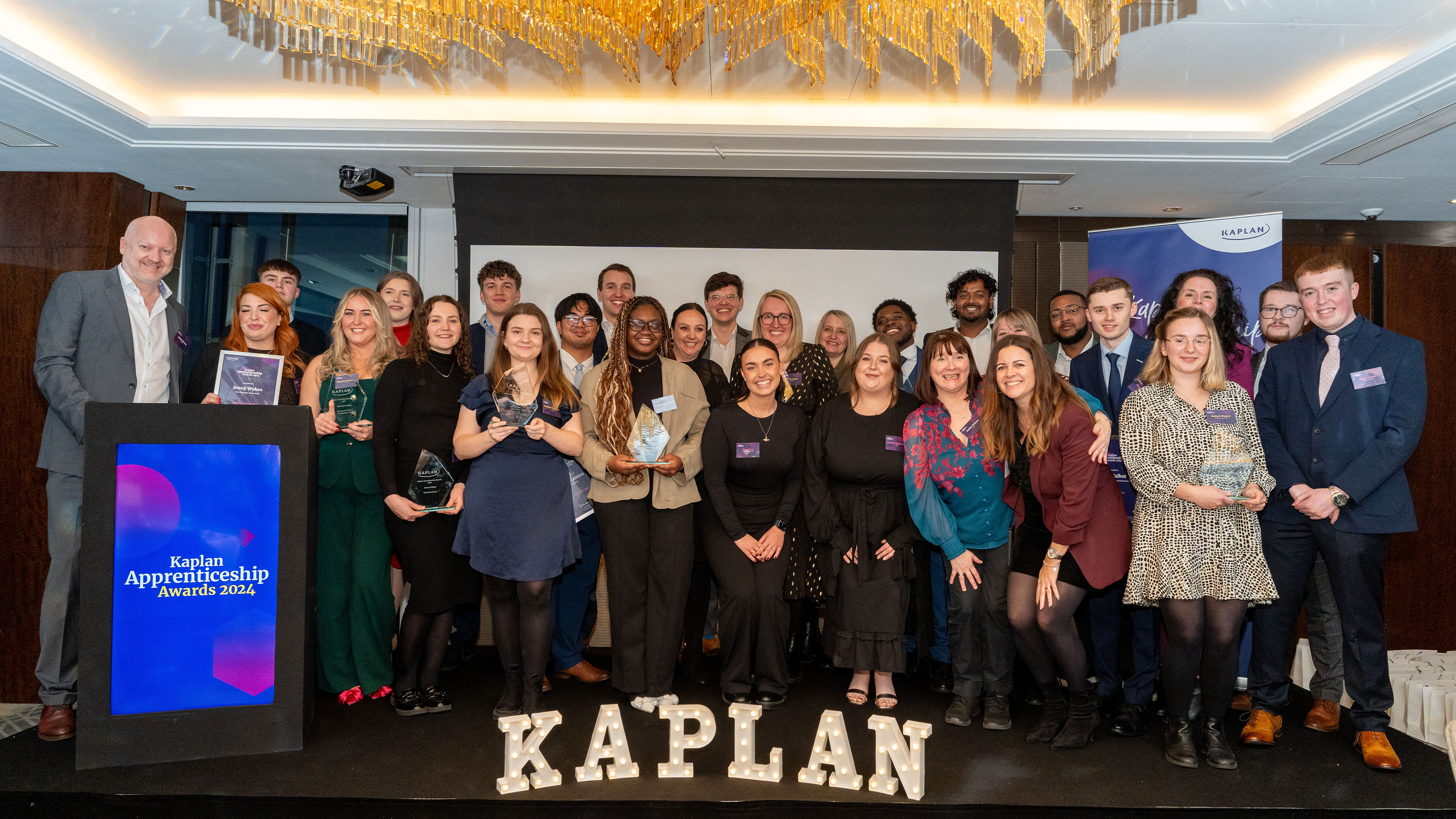 Group of people at awards with Kaplan sign in front of them