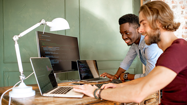 two men working on computers on desk