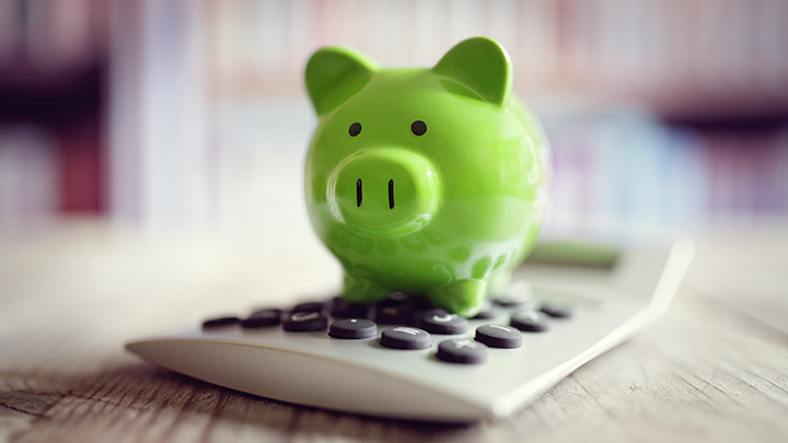 A green piggy bank on top of a white calculator