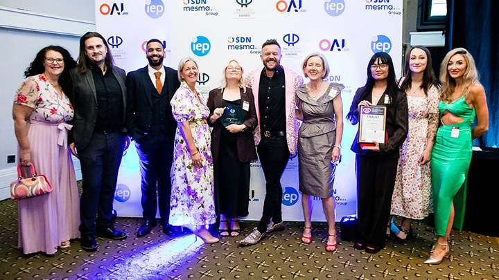 The Kaplan compliance team at an awards ceremony posing together in formal attire against a branded backdrop.