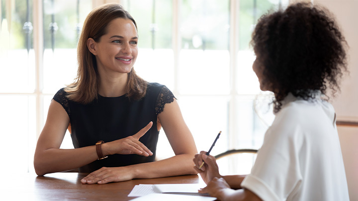 Two women talking across a desk