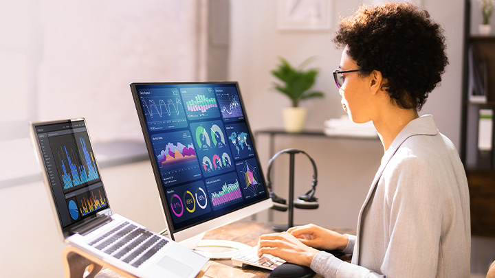 Woman working at laptop and computer screen