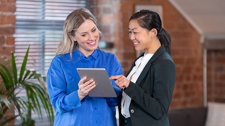 Two women talking and looking at a tablet computer