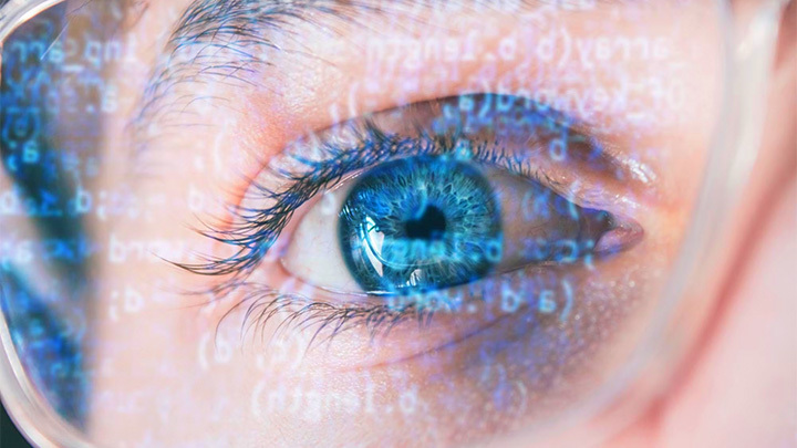 A close up of an eye with a soft overlay of coding language in glowing text