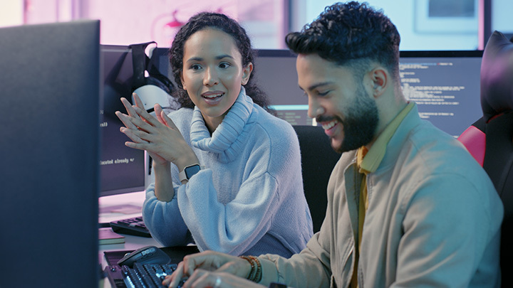 Man and woman working at computers talking and smiling at each other