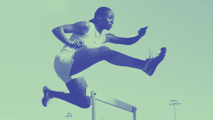 Female athlete jumping over hurdle