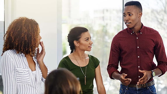 A man and two women standing and talking