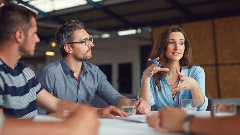 A woman and two men having a discussion around a table