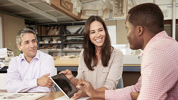 Two men and a woman using a tablet during a meeting