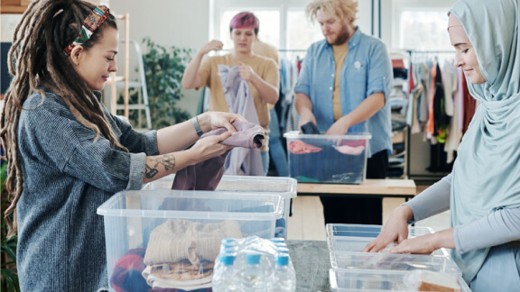 A group of people organising clothes into boxes