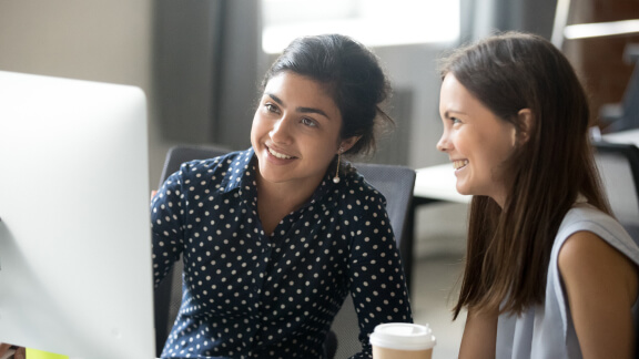 Two women looking at a computer screen and smiling