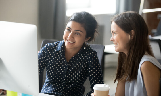 Two women looking at a computer screen and smiling