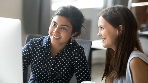 Two women looking at a computer screen and smiling