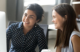 Two women looking at a computer screen and smiling