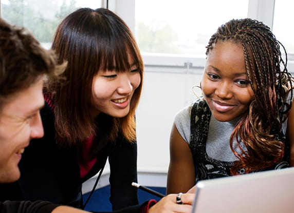 Two woman and a man looking at a laptop
