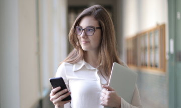 A woman holding a mobile phone and a folder of papers.