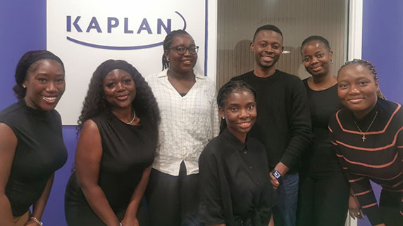 A group of seven black interns next to the Kaplan logo