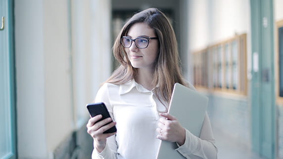 A woman holding a mobile phone and a folder