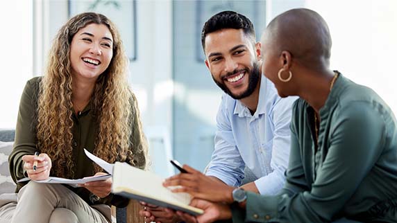 Two women and a man sitting down, talking and smiling