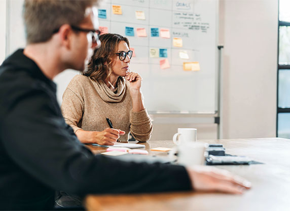Man and a woman sat around a desk in a meeting room