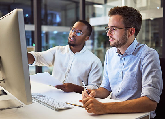 A man showing something on a monitor to another man