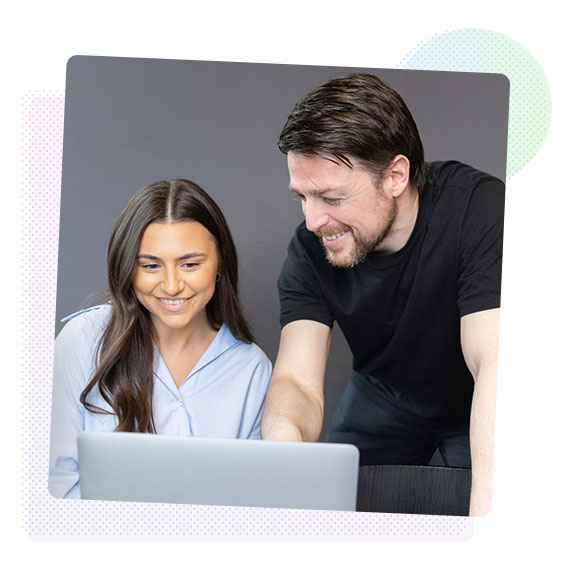 A woman and a man looking at a computer screen and smiling.