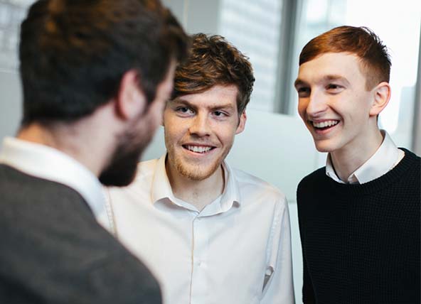 Three men standing up talking