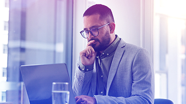 Man in glasses working on laptop.