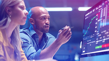 Man and woman looking at a screen with graphical data