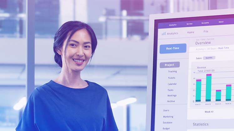 Woman smiling beside a laptop screen