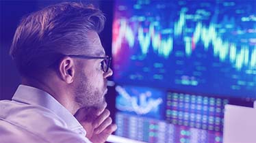A man wearing glasses looking at a screen with data graphics 