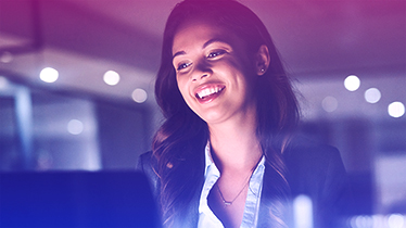 A woman smiling and looking at a laptop.