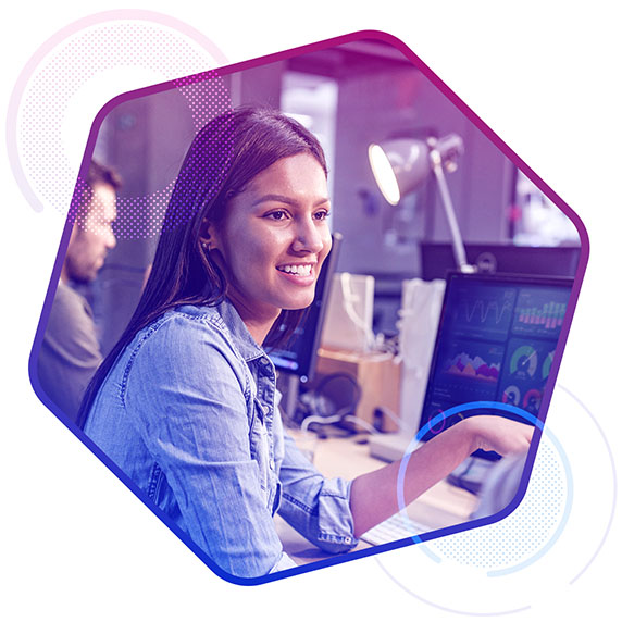 A women with data charts on a monitor in front of her looking at a colleague