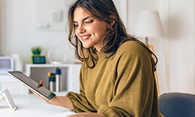 Woman holding a tablet device while flicking through a book