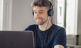 Man wearing headphones looking at a laptop screen.
