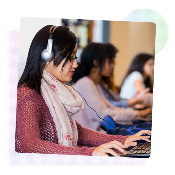 Woman in an office working on a computer wearing a headset