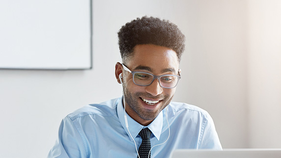 Man wearing headphones looking at a laptop screen