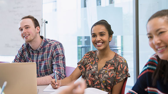 Two women and a man sat at a desk