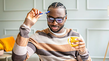 A man scratching his head with a pen