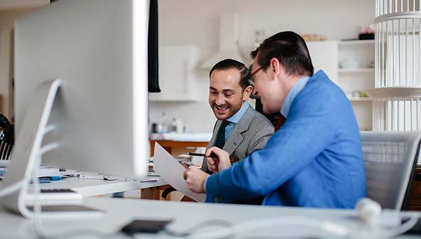 Two men sat down at a desk having a discussion