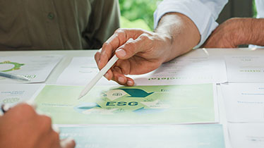 A hand holding a pen pointing to a piece of paper