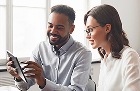 A man showing a woman something on a tablet.
