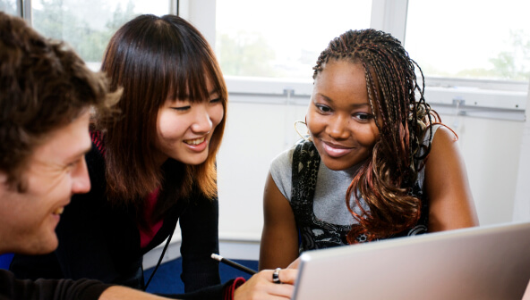 Two women and a man looking at a laptop