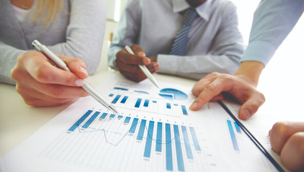 A woman and two men looking at bar charts and pie charts.