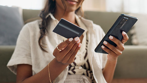 Woman holding a phone in one hand and a credit card in the other