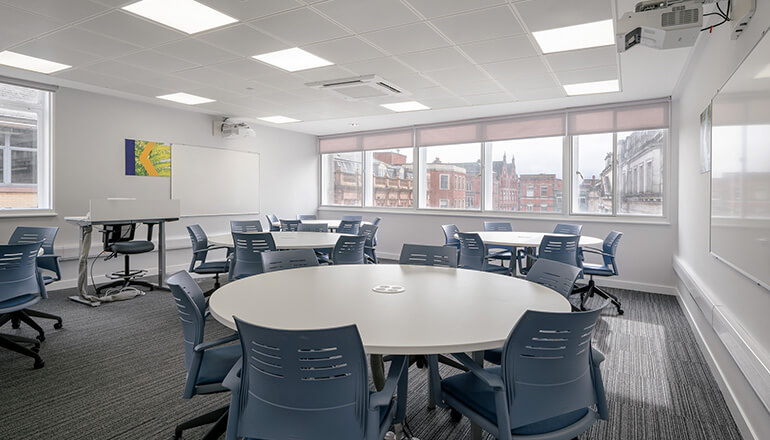 A classroom with round tables and interactive whiteboards